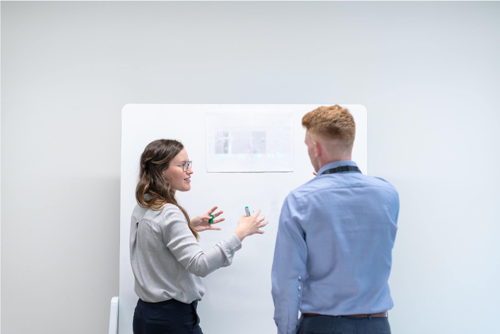 two people discussing and looking at whiteboard