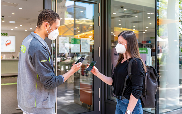 two people with masks holding phones
